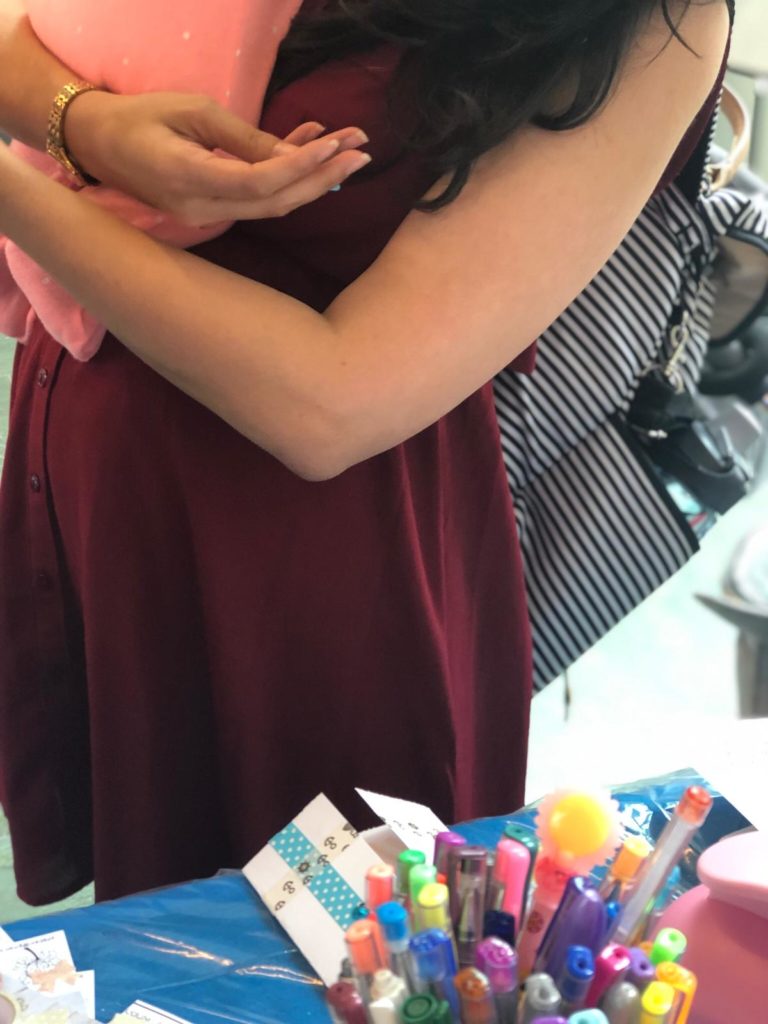 שולחן עם חומרי יצירה, יומן ויזואלי שאמא עוסקת באומנות בזמן חופשת הלידה כשאוחזת בתינוקה אחרי לידה